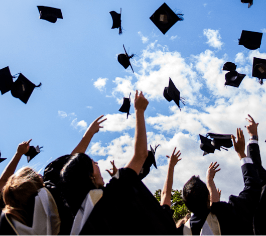 Graduates tossing mortarboards into the air.